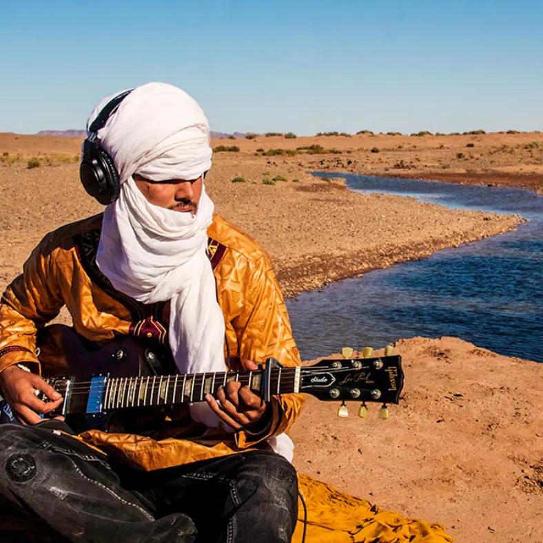 Musicien touareg à la guitare électrique au bord de l'oued Drâa, esprit Blues du désert